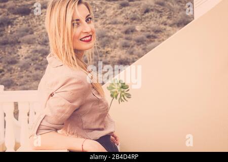 Jolie fille blonde caucasienne souriant et regardez l'appareil photo dans un style vintage portrait de mode - extérieur jeune femmes séduisantes avec des vêtements à la mode et le style de vie Banque D'Images