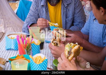 Les gens méconnaissables mangeant le hamburger ensemble à la maison sur la table pour le déjeuner - concept malsain de la nourriture de pourries et de perte de poids de régime - la restauration rapide de près Banque D'Images