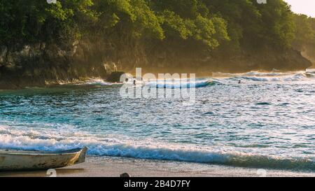 Les enfants surfent sur les vagues dans le coucher du soleil la lumière, Belle Baie Cristal, Nusa Penida, Bali Banque D'Images