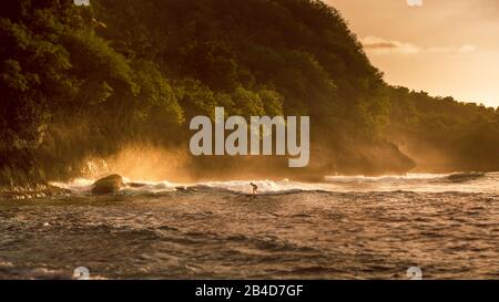 Les enfants surfent sur les vagues dans le coucher du soleil la lumière, Belle Baie Cristal, Nusa Penida, Bali Banque D'Images