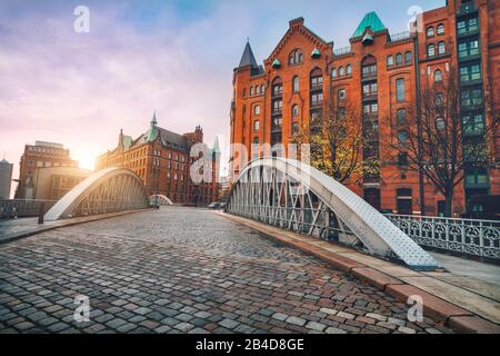 Pont d'arche sur les canaux d'Alster avec rue pavée dans le quartier historique de Speicherstadt, coucher de soleil, Hambourg, Allemagne, Europe, Banque D'Images