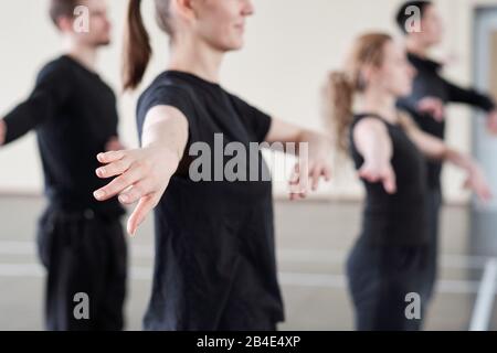 Main de jeune femme active dans un t-shirt noir exerçant à la leçon en studio de danse sur le fond d'autres étudiants Banque D'Images
