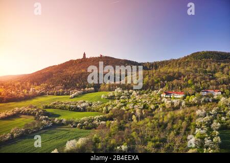 Allemagne, Thuringe, frontière avec Saxe-Anhalt, vergers en fleurs, collines avec le monument Kyffhäuser, troisième monument allemand, soleil radiant du matin Banque D'Images