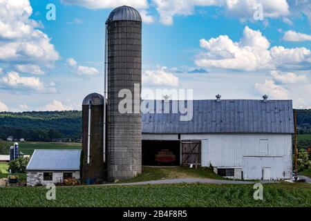 Strasburg, PA / USA - 27 juin 2017: Une grande grange blanche avec deux silos dans le comté rural de Lancaster, Pennsylvanie. Banque D'Images