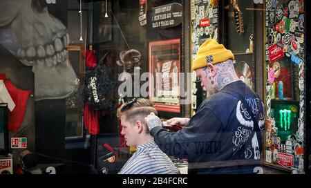 Barber au travail dans l'arcade High Street, Cardiff, Pays de Galles du Sud Banque D'Images