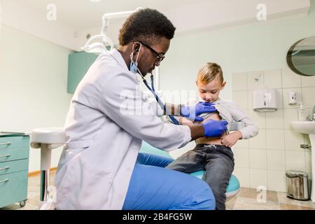 Médecin et patient africain américain. Le médecin examine le petit garçon par stéthoscope. Concept de médecine et de thérapie pour enfants. Banque D'Images