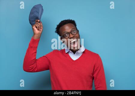 Portrait d'un homme africain souriant mettant un chapeau pour accueillir son ami et regarder l'appareil photo. Bonjour, je suis heureux de vous voir. Visage humain positif Banque D'Images