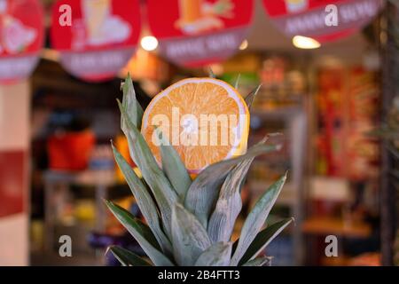 Morceau d'orange coupé sur les feuilles d'ananas. Il a été tiré devant un magasin qui a fait du jus de fruits. Gros plan. Banque D'Images