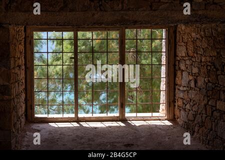 Vue par une fenêtre barrée sur les pins, l'île de lèpre Spinalonga, la Grèce, la Crète, Kalydon Banque D'Images