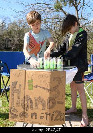 L'assainisseur pour les mains remplace la limonade alors que les jeunes entrepreneurs Miles Miller et Louis Spindlersell vendent de l'assainisseur pour les mains maison pour aider à combattre le coronavirus pour 3 $ la bouteille dans leur quartier d'Austin, Texas, après l'école. Banque D'Images