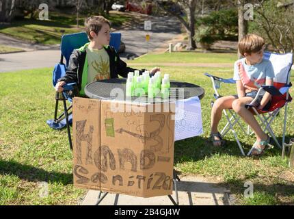 L'assainisseur pour les mains remplace la limonade alors que les jeunes entrepreneurs Miles Miller et Louis Spindlersell vendent de l'assainisseur pour les mains maison pour aider à combattre le coronavirus pour 3 $ la bouteille dans leur quartier d'Austin, Texas, après l'école. Banque D'Images