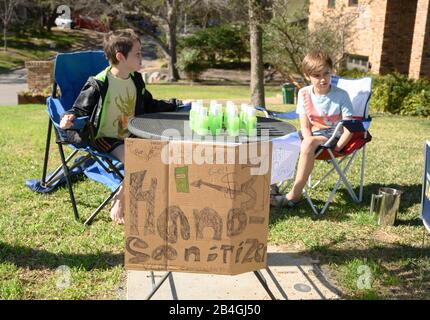 L'assainisseur pour les mains remplace la limonade alors que les jeunes entrepreneurs Miles Miller et Louis Spindlersell vendent de l'assainisseur pour les mains maison pour aider à combattre le coronavirus pour 3 $ la bouteille dans leur quartier d'Austin, Texas, après l'école. Banque D'Images