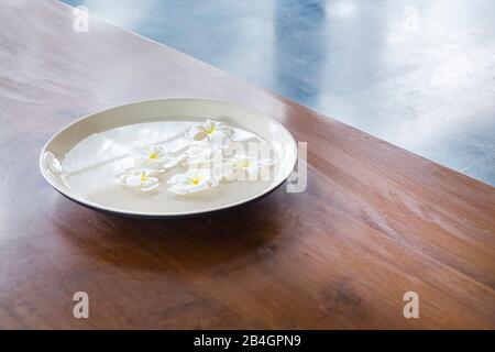 Fleurs dans une tasse d'eau sur table en bois Banque D'Images