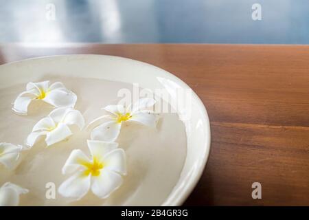 Fleurs dans une tasse d'eau sur table en bois Banque D'Images