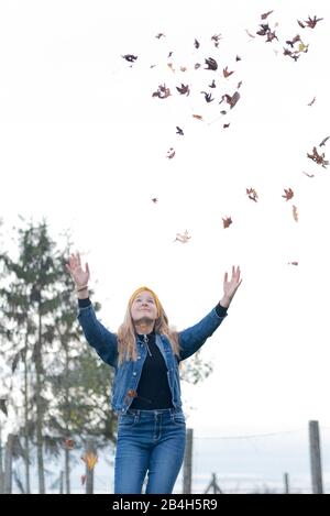 Une jeune fille de douze ans jette les feuilles dans l'air et aime la chute Banque D'Images