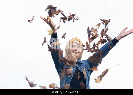 Une jeune fille de douze ans jette les feuilles dans l'air et aime la chute Banque D'Images