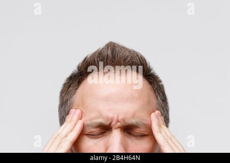 Maux de tête, tension nerveuse, concept temporel et de douleur de vol. Gros portrait de l'homme massant ses temples, œil fermé, isolé sur le backgroun gris Banque D'Images