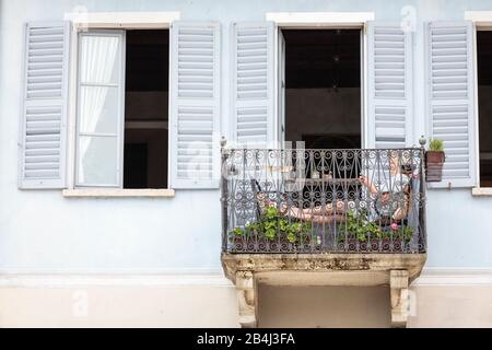 Europa, Italien, Piemont, Cannobio. Eine Frau sitzt auf einem kleinen Balkon und lile. Banque D'Images