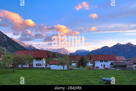 Maisons au bord du village au soleil le soir contre le groupe Estergebirge Zugspitze 2962 m dans les montagnes Wetterstein et les Alpes d'Ammergau, Ohlstadt, Loisachtal, Zugspitzland, Haute-Bavière, Bavière, Allemagne Banque D'Images