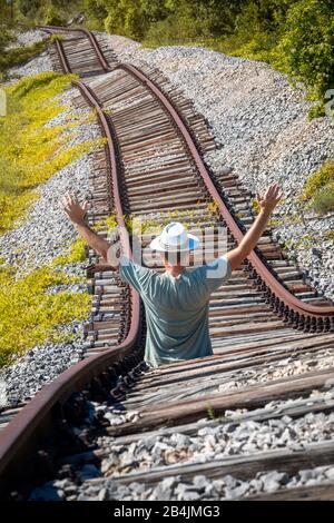 L'homme avec un chapeau blanc au milieu de rails abandonnés semble vouloir arrêter un train imaginaire, Pijana pruga, Kozljak, Krsan, Istrie County, Croatie Banque D'Images