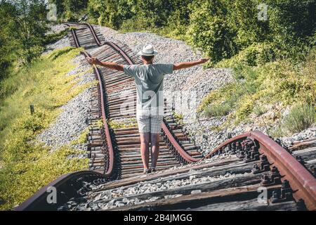 L'homme avec un chapeau blanc au milieu de rails abandonnés semble vouloir arrêter un train imaginaire, Pijana pruga, Kozljak, Krsan, Istrie County, Croatie Banque D'Images