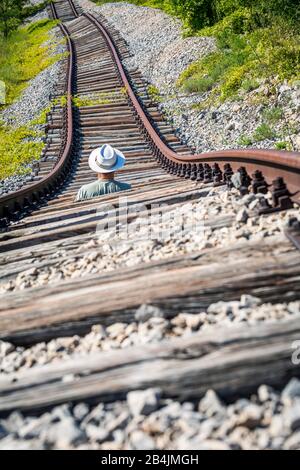 Homme avec chapeau blanc au milieu de rails abandonnés attendant un train imaginaire, Pijana pruga, Kozljak, Krsan, Istria County, Croatie Banque D'Images