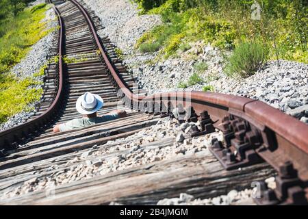 Homme avec chapeau blanc au milieu de rails abandonnés attendant un train imaginaire, Pijana pruga, Kozljak, Krsan, Istria County, Croatie Banque D'Images