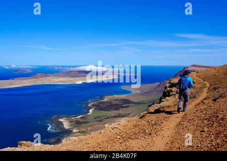 Femme avec des promenades à dos sur le bord de la falaise, l'île de la Graciosa, vue de Risco de Famara, Lanzarote, îles Canaries, Espagne Banque D'Images