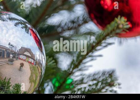 L'Allemagne, le Mecklembourg-Poméranie occidentale, Prerow, une maison traditionnelle avec un toit de chaume se reflète dans une boule de Noël Banque D'Images