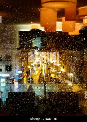 Feux de rue derrière les fenêtres pluvieuses et reflet de l'éclairage intérieur Banque D'Images