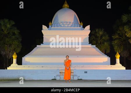 Luang Prabang, Laos - 2019-11-18: Portrait d'un jeune moine bouddhiste devant le stupa Que Pathoum au temple Wat Wisunarat, la nuit. Banque D'Images