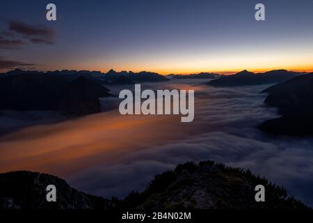 Les lumières de Maurach et de Pertisau sur le lac Achensee brillent sous la mer des nuages du brouillard élevé qui monte pendant une exposition de nuit à long terme. En arrière-plan, les montagnes de Karwendel, prises de l'Ebener Joch dans le Rofan. Banque D'Images