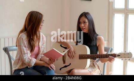 Vue rapprochée de deux jeunes filles de collège prendre une courte pause et jouer de la guitare dans le salon moderne Banque D'Images