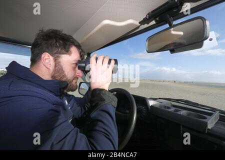 Saint-Pierre Ording, Allemagne. 01 mars 2020. Le chasseur de phoques Toni Thurm regarde à travers des jumelles sur la plage. Malgré son nom, le chasseur de phoques ne chasse pas les phoques, mais les prend en compte. Il est formé pour aider les phoques malades et blessés et les phoques gris. Crédit: Wolfgang Runge/Dpa/Alay Live News Banque D'Images