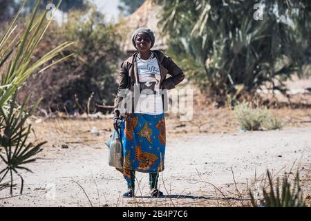 Kapako, Kavango West, Namibie - 29 Juillet 2019: Femme Noire Locale Transportant Des Sacs En Plastique Avec Réservoir D'Eau Banque D'Images