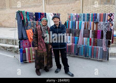 Vendeurs amicaux à leur stand de foulards traditionnels colorés, Boukhara, Ouzbékistan Banque D'Images