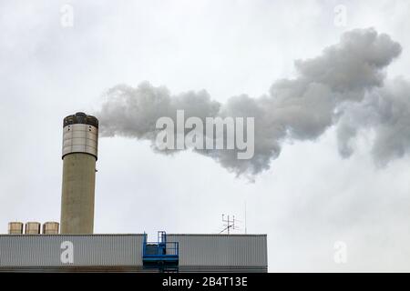 Centrale avec cheminée émettant des gaz dans l'atmosphère, provoquant la pollution de l'air. Gris, ciel nuageux. Banque D'Images