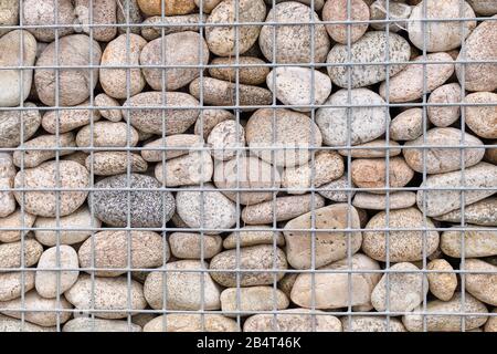 Mur avec pierres lisses dans une grille. Contexte. Gros plan. Banque D'Images