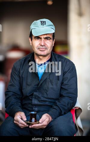 Irak, Kurdistan Irakien, Arbil, Erbil. Le patron d'un fleuriste à Etbil pose avec une tasse de thé devant son magasin Banque D'Images