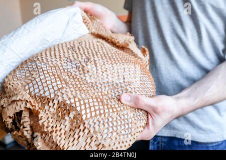 Tenez un article fragile emballé. Emballage en papier sous forme de grille. Papier d'emballage intéressant. Banque D'Images