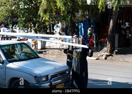 Irak, Kurdistan Irakien, Arbil, Erbil. Deux hommes déchargent le matériau de construction d'une voiture. Banque D'Images