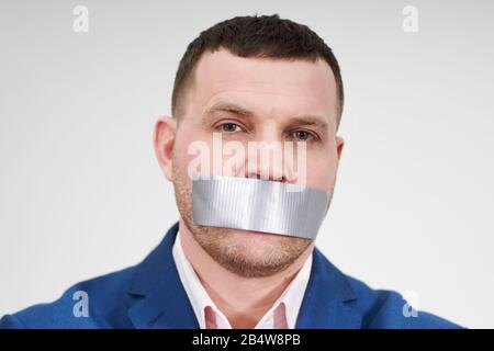 l'homme a un gros morceau de ruban industriel noir couvrant sa bouche, concept de silence Banque D'Images