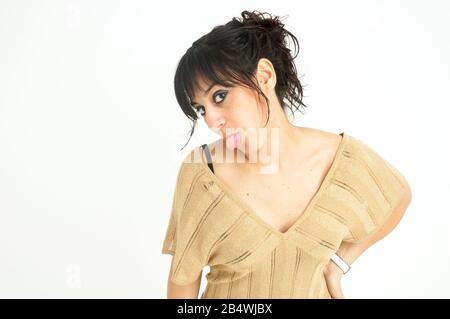 jolie fille qui colle sa langue regardant l'appareil photo, avec les cheveux recueillis, sur fond blanc, photo moyenne Banque D'Images