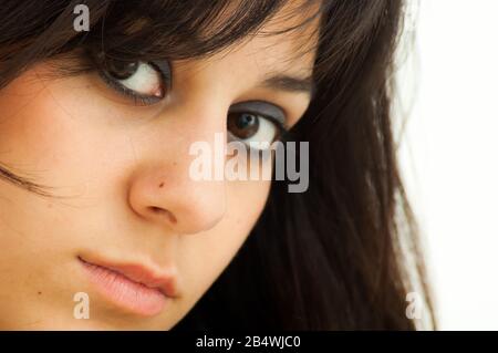 Jolie fille brunette regardant tout droit, sur fond blanc, gros plan Banque D'Images