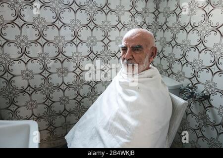 Vieil homme Affamé dans l'appareil photo Tout En attendant sa coupe de cheveux Banque D'Images