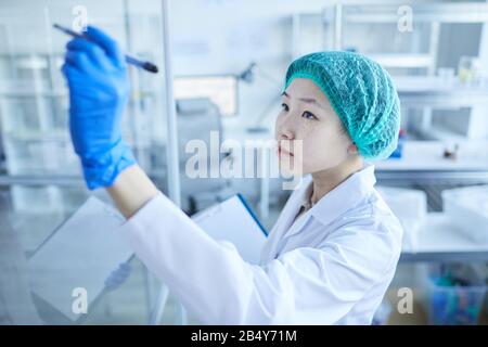 Gros plan horizontal moyen de la photo haute angle des femmes scientifiques asiatiques de laboratoire écrivant des formules sur le mur de verre Banque D'Images