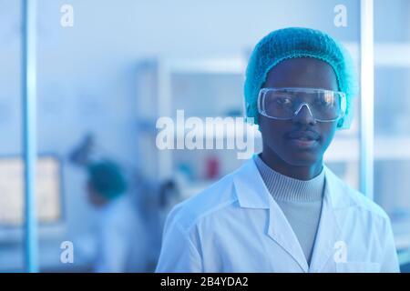 Tête horizontale et épaules portrait de beau jeune homme portant un blouse de laboratoire blanc, une casquette médicale et des lunettes de protection regardant l'appareil photo Banque D'Images