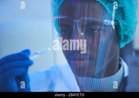 Portrait horizontal de gros plan de jeune scientifique de laboratoire masculin africain tenant une ampoule avec un nouveau vaccin qu'il a développé Banque D'Images