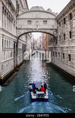 En regardant le canal alors qu'un petit bateau à moteur passe sous le pont des Soupirs à Venise, Italie, lors d'une matinée hivernale brumeuse et froide en décembre Banque D'Images