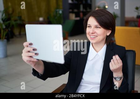 Jeune femme d'affaires ayant un appel vidéo avec une tablette pendant une pause de conflit Banque D'Images